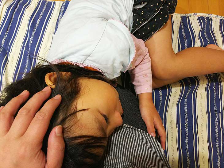 腹痛で母親に膝枕をしてもらっている女の子