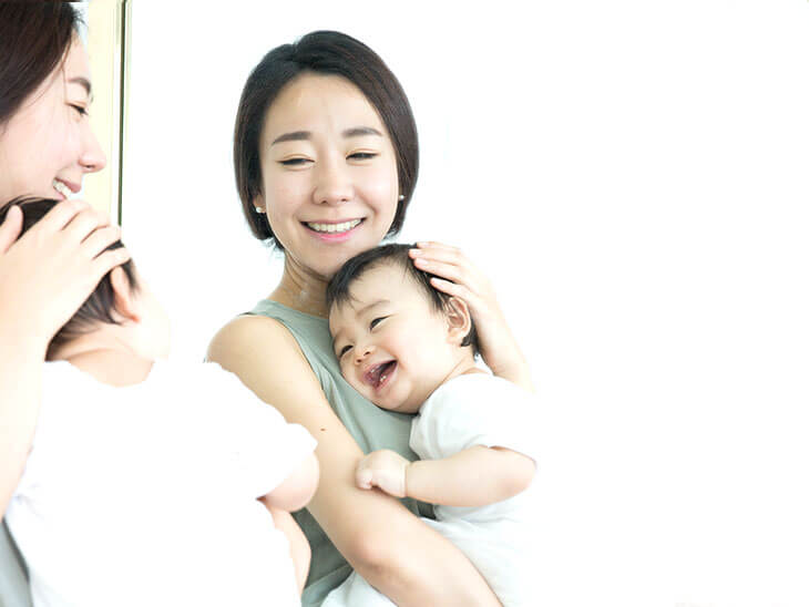 鏡に映る笑顔の母親と赤ちゃん