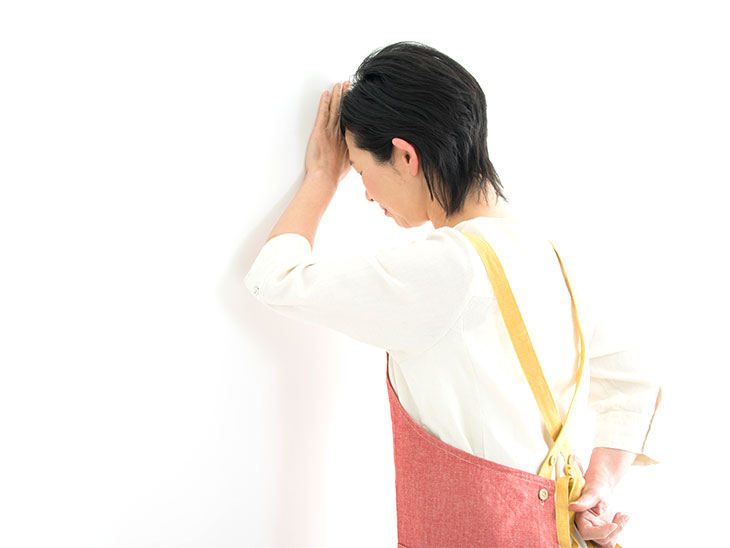 壁にもたれて落ち込む母親