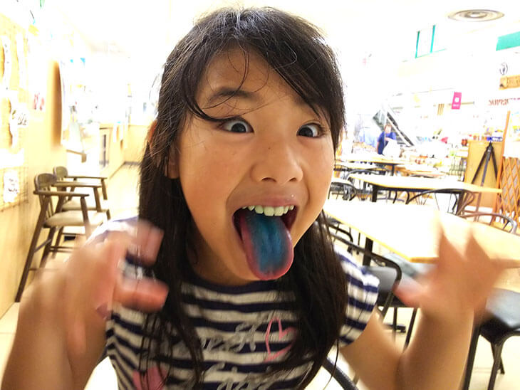 着色料で染まった舌を見せる子供