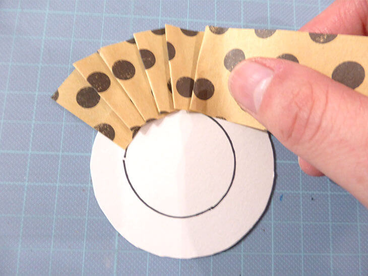 円に合わせて折り紙をプリーツにしながら貼る様子