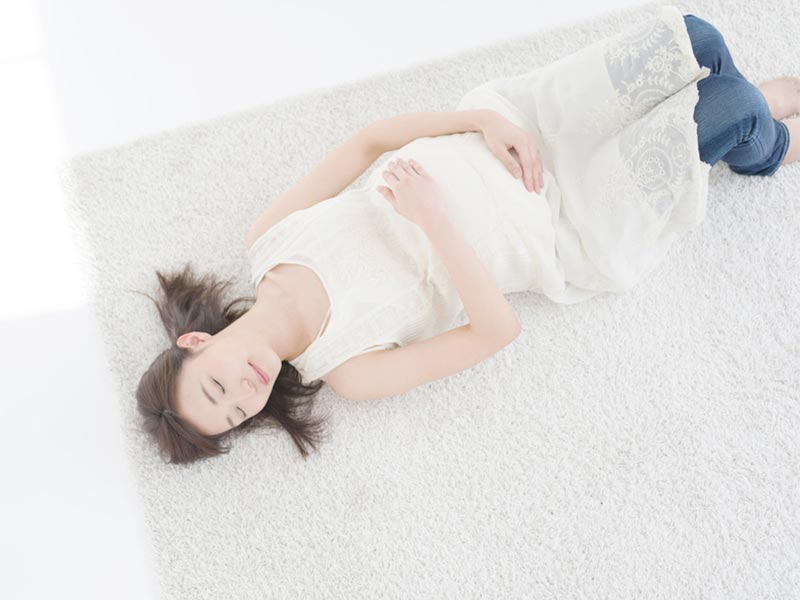 仰向けになって寝ている若い妊婦さん
