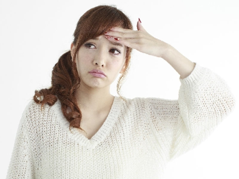 額に手をあてて熱を測ってる風邪をひいた妊婦