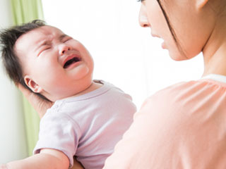 泣く赤ちゃんを抱く母親