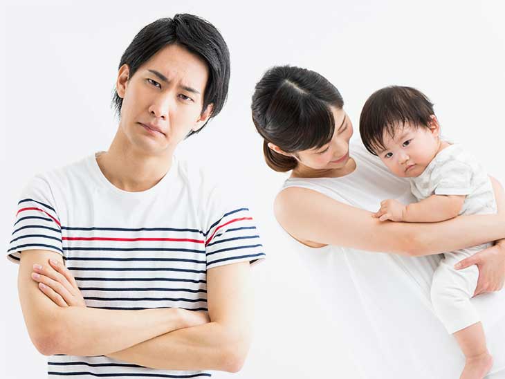 赤ちゃんを抱っこしているママに相手にされず困り顔のパパ