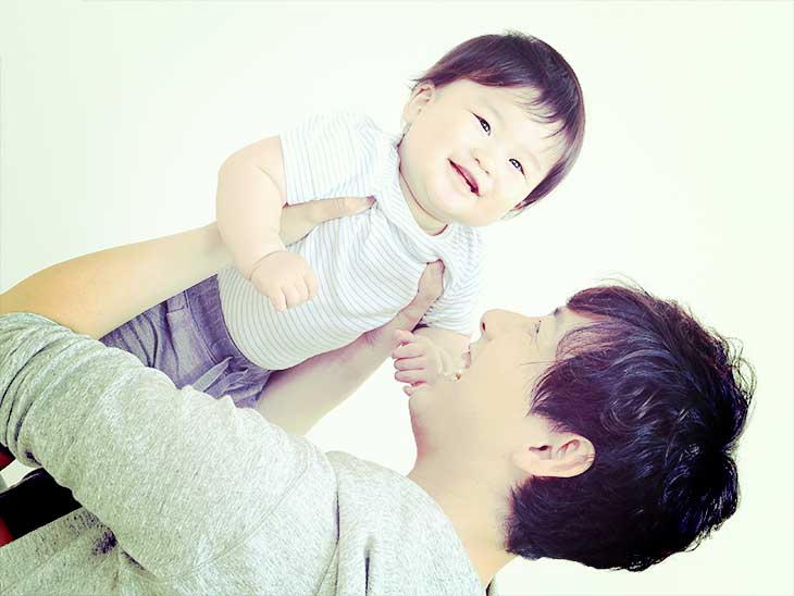 笑顔の赤ちゃんを高い高いして笑っている若い父親