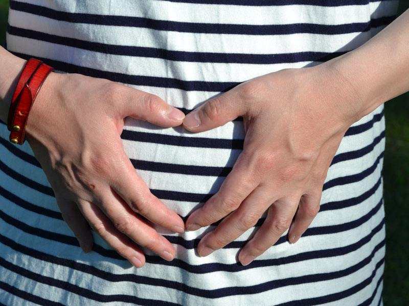 しましまのシャツを着てるお腹を触ってる妊婦さん