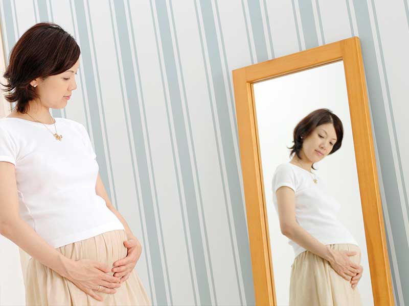 鏡で自分のお腹を見る妊婦さん