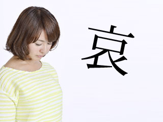 うつむく女性と哀の文字