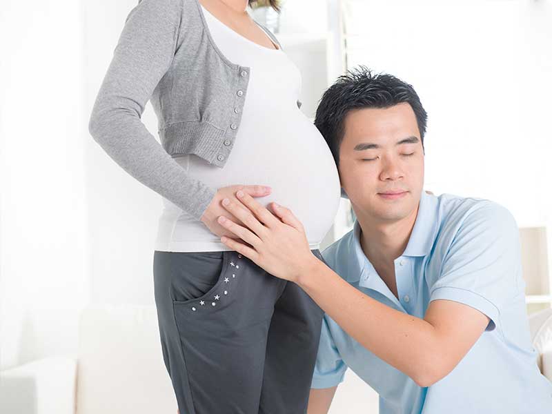 奥さんのお腹耳をあてている旦那さん