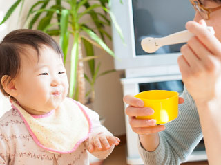 母親から離乳食をもらう赤ちゃん