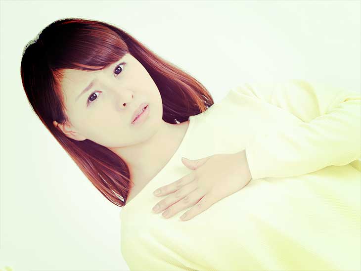 動悸を気にして胸に手をあてている女性