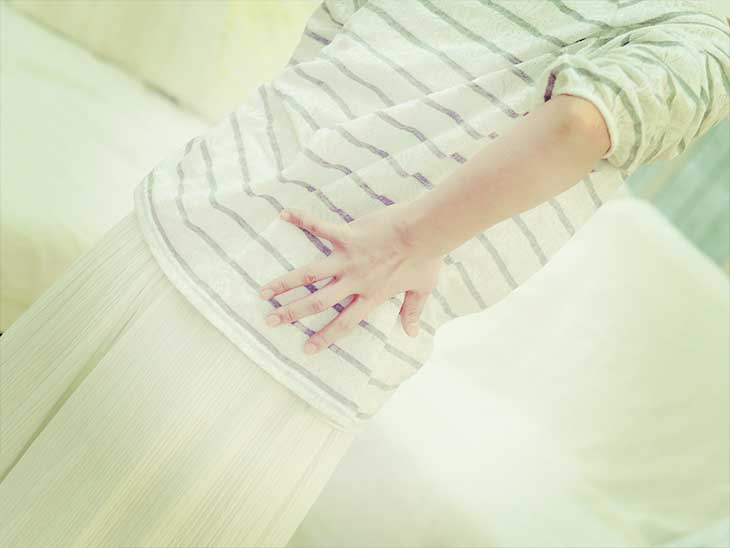 腰が痛くて手でおさえている女性