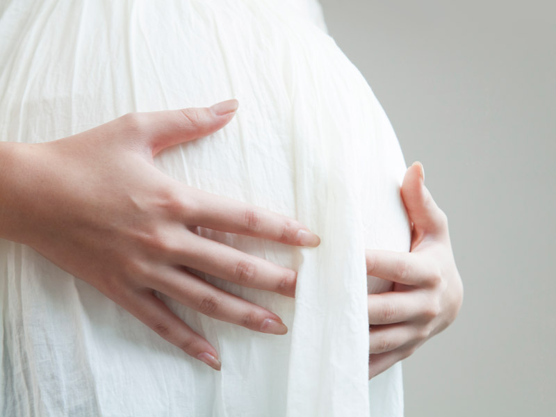 おなかの回りに手を当てている妊婦さん