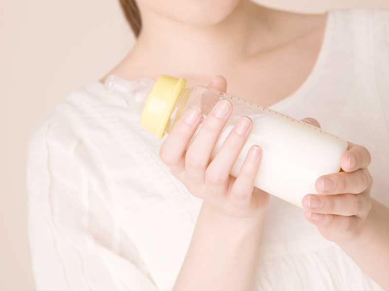 ミルクの入った哺乳瓶を持つ女性の手