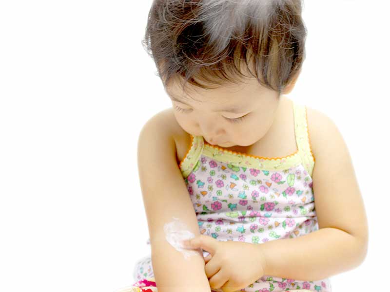 自分の腕にローションを塗る小さい女の子
