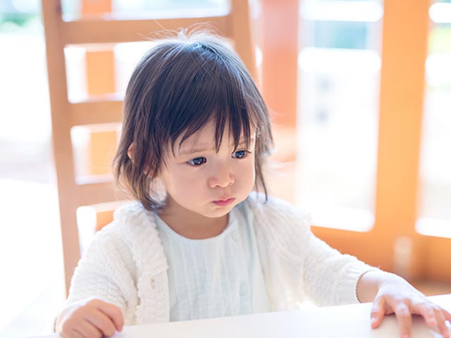 椅子に座って黙り込む幼児