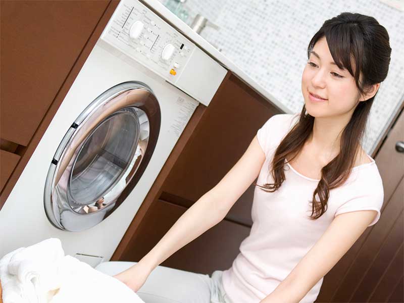 乾燥機付き洗濯機に洗濯物を入れようとしている女性